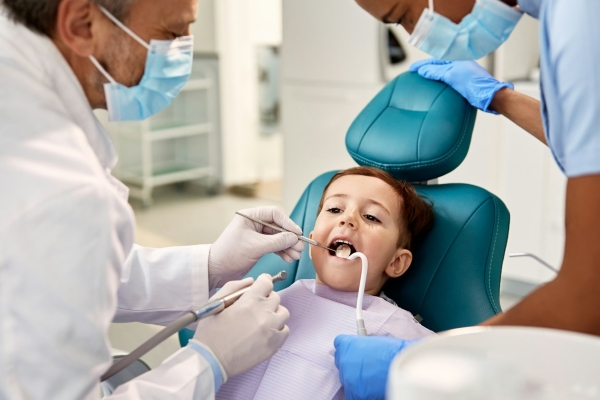 Little boy having dental examination by two dentists at dental clinic.