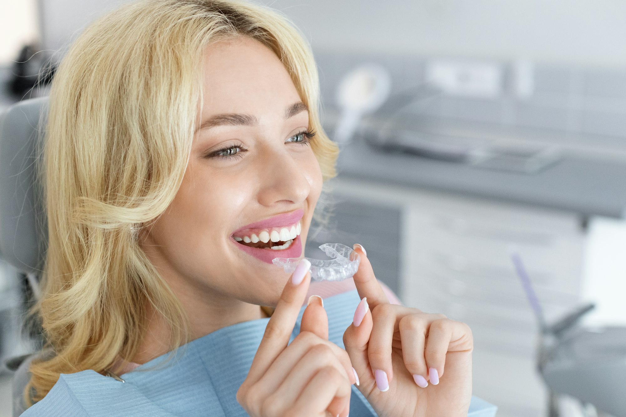 Young attractive woman holding invisible braces or trainer